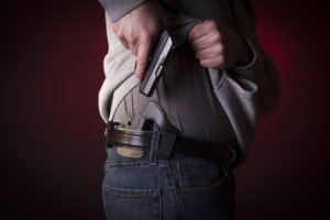 A man pulling his gun out of its holster, that was concealed by his jacket