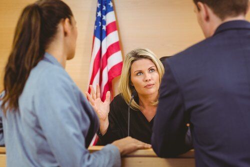 Two California attorneys conferring with judge at sidebar with an American flag in the background