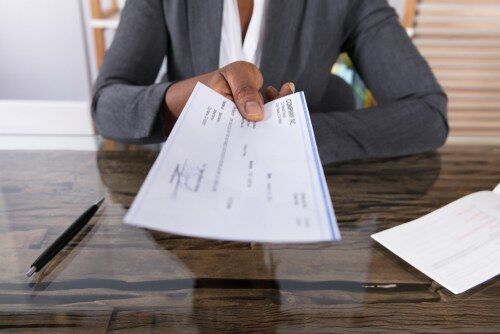 woman at desk handing over a paycheck