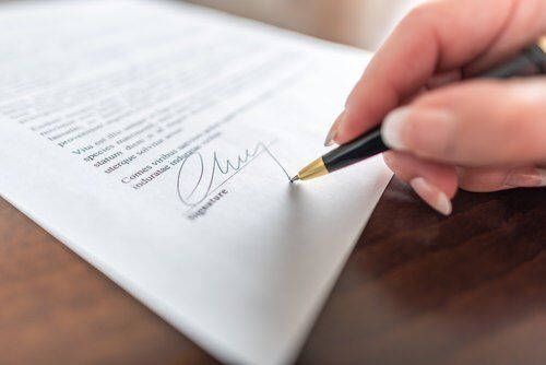 Hand and pen signing a document