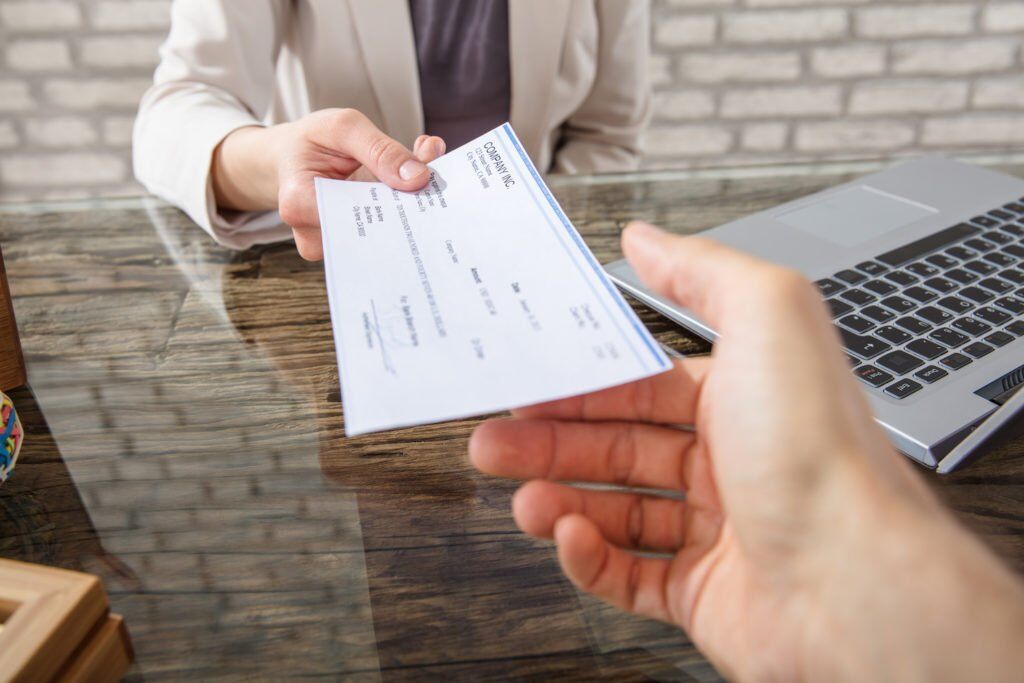 Close-up of employer handing check to employee 