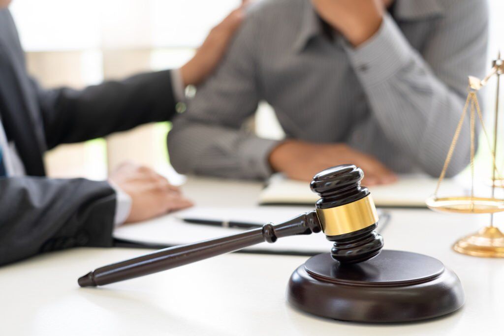 Attorney comforting client with gavel in foreground