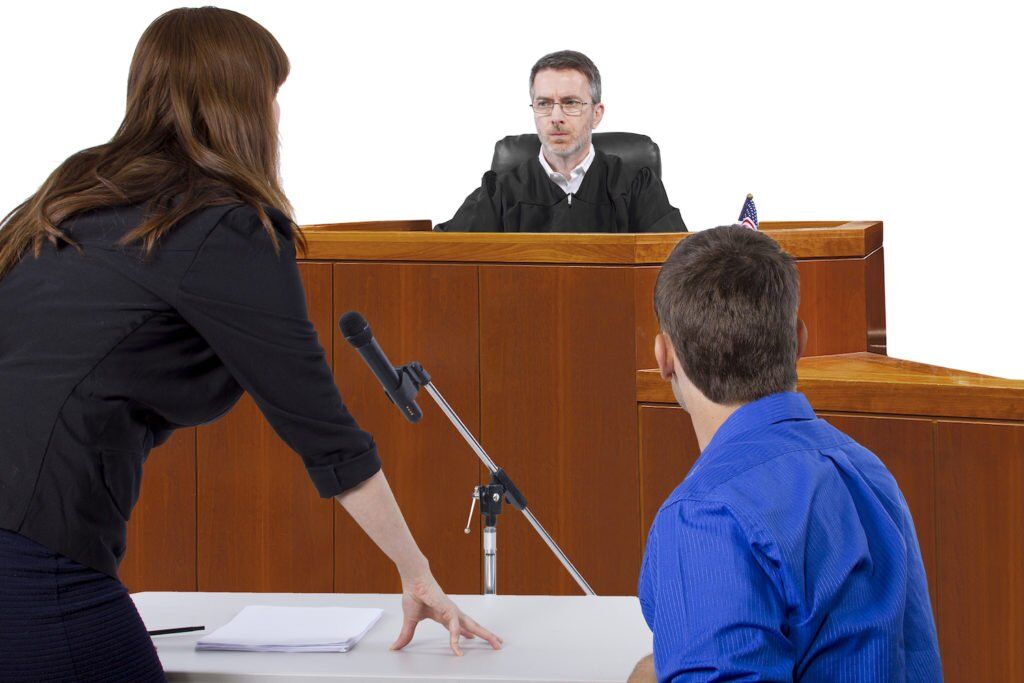 Parole violation hearing with judge in background and the defendant and defense attorney in foreground