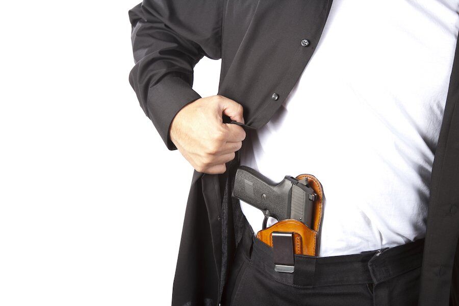 Man pulling back shirt to reveal gun tucked into pants