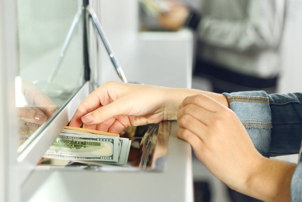 Person handing cash to a teller.