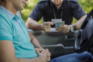 A police officer asking a driver for his license and insurance.