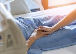 Caregiver holding patient hand in hospital