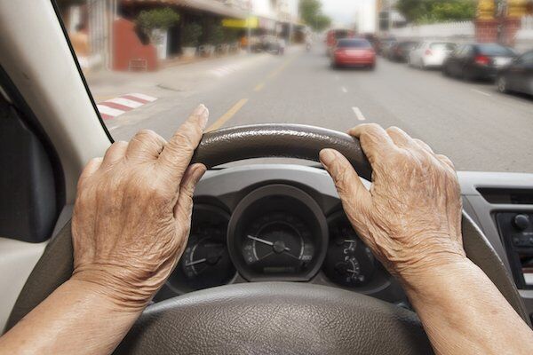 Closeup of elderly hands behind the wheel