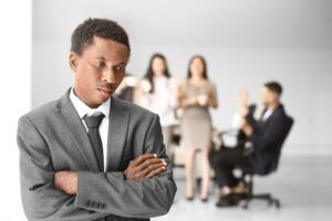 Victim of workplace discrimination looking forlorn with three co-workers in the background